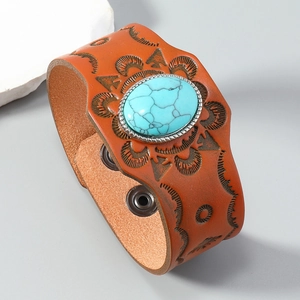 Macro detail of bohemian leather bracelet with embossed sun patterns and turquoise stone
