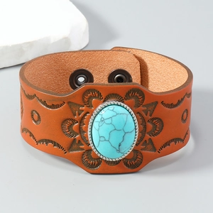 Detail of bohemian wide leather bracelet with embossed patterns and turquoise stone inlay
