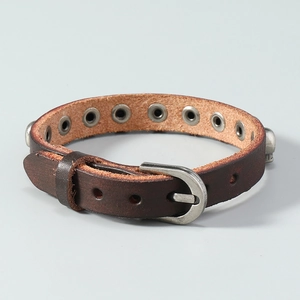 Détail d'un bracelet punk en cuir marron avec des œillets métalliques et un crâne argenté