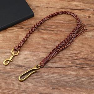 Dettaglio della catena per pantaloni in pelle intrecciata vintage con ganci e nappe in bronzo