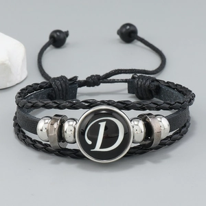 Macro detail of multi-layer leather bracelet featuring braided cords and letter D charm