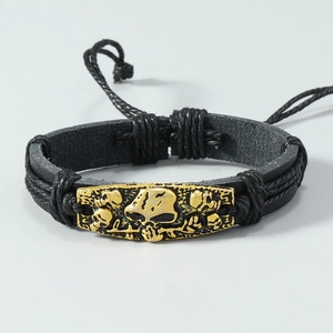 Detail of hand-woven leather bracelet with antique gold skull charm and adjustable cord