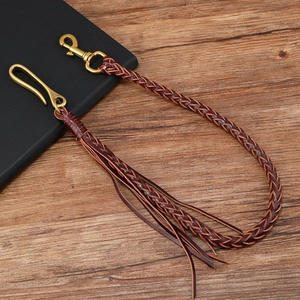 Dettaglio catena per pantaloni in pelle intrecciata marrone con ganci e nappe in bronzo