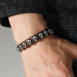 Détail d'un bracelet punk en cuir marron foncé orné de huit crânes en alliage argenté