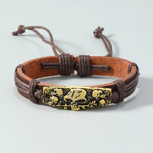 Macro view of brown braided leather bracelet with vintage golden skull metal plaque