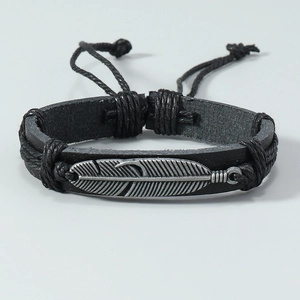 Détail d'un bracelet en cuir noir tressé à la main avec pendentif plume argenté vintage