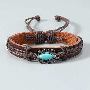 Détail d'un bracelet en cuir marron vintage avec pierre turquoise et cordes tressées