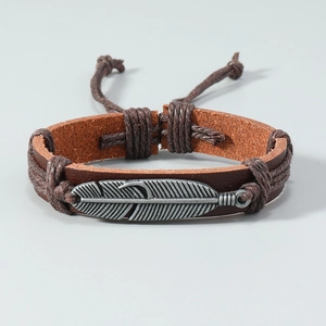 Détail d'un bracelet en cuir vintage avec pendentif plume en métal argenté et cordon tressé