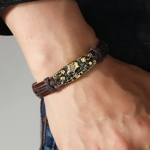 Handmade woven leather bracelet featuring a vintage gold-toned skull engraved plaque