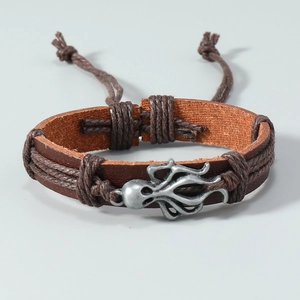 Macro shot of vintage brown leather woven bracelet with silver octopus metal charm