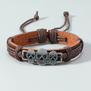 Detalle de pulsera de cuero trenzado a mano con tres calaveras plateadas para hombre
