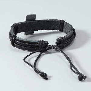 Detail of hand-woven leather bracelet with a vintage metal cross and adjustable cord