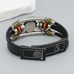 Detalle de pulsera multicapa de cuero negro con cuentas de metal y cierre de botón a presión