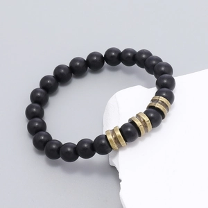 Détail d'un bracelet artisanal avec perles noires mates et entretoises en métal bronzé