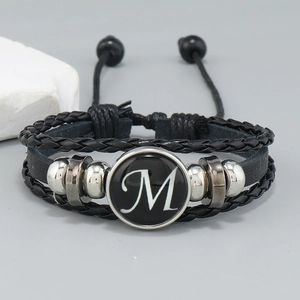 Macro detail of multi-layer leather bracelet with a white serif M letter charm