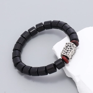 Detail of handmade black wooden bead bracelet with textured silver square and red accents