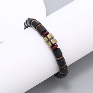 Detail of beaded men's bracelet with black wood beads and vintage brass cross charm