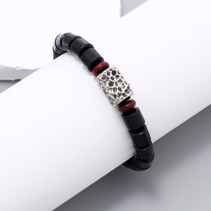 Detail of beaded bracelet with black matte wood beads and hammered silver metal charm