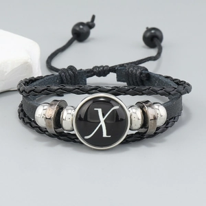 Detail of layered black leather bracelet with silver beads and letter X glass charm