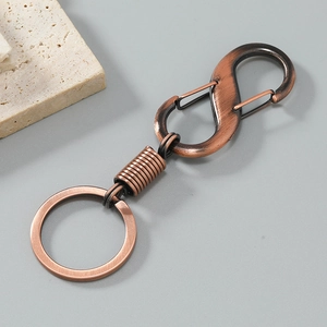 Close-up of retro copper alloy car keychain with dual S-hook and spring detail