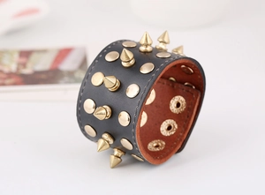 Detail view of black punk leather bracelet with gold cone spikes and round metal studs