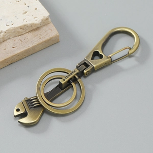 Vintage bronze wrench keychain with double rings and heart cutout on dark background
