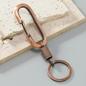 Detail of vintage copper car keychain with spring clip and D-ring on stone background