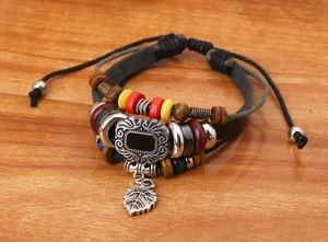 Close-up of multilayer leather bracelet with wooden beads and silver leaf pendant
