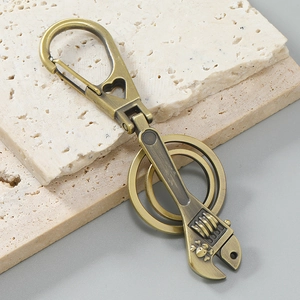 Detail of vintage bronze wrench keychain with skull engraving and heart-shaped carabiner