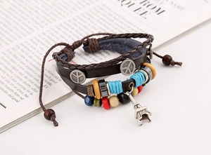 Close-up of multilayer leather bracelet set with Eiffel Tower charm and peace symbol