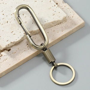 Close-up of vintage bronze spring keychain with carabiner on stone background