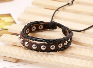 Detail of multi-layer leather bracelet featuring silver studs and woven black cord