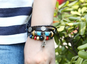 Detail of multilayer woven leather bracelet featuring peace signs and Eiffel Tower charm