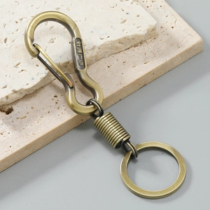 Detail of vintage bronze S-hook keychain with embossed characters on stone surface