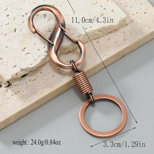 Vintage bronze alloy car keychain with S-carabiner and spring design on stone surface