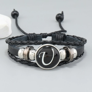 Detail of layered black leather bracelet with letter V bead and metallic accents