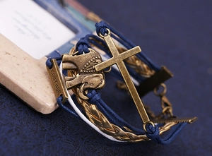 Détail d'un bracelet tissé avec pendentif éléphant, croix et barre en métal gravée