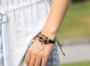 Detail of bohemian multilayer leather bracelet with colorful wood beads and leaf charm
