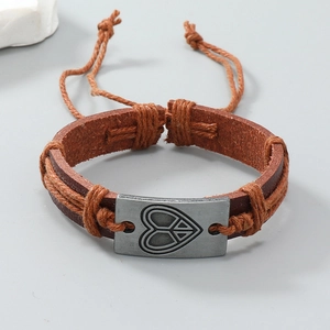 Gros plan d'un bracelet en cuir tressé avec plaque en métal vintage et symbole de paix