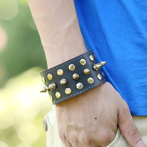 Punk black leather wide bracelet with gold round studs and metal spikes on person arm