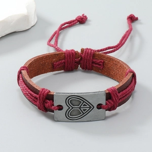 Détail d'un bracelet en cuir tressé à la main avec breloque cœur et symbole de paix