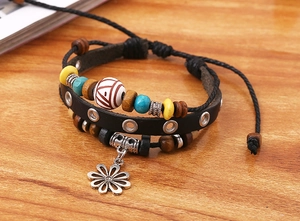 Detail eines mehrlagigen Lederarmbands mit Holzperlen und silbernem Blumenanhänger