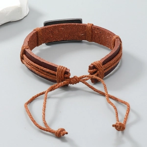 Détail du bracelet en cuir vintage marron avec plaque en métal gris et cordon réglable