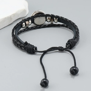 Macro detail of black braided leather bracelet with silver beads and snap button