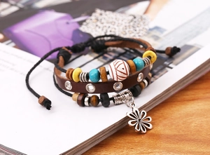 Detail eines mehrlagigen Lederarmbands im Boho-Stil mit Holzperlen und Gänseblümchen