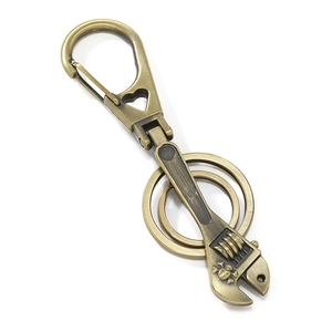 Retro bronze wrench keychain with skull charm and double rings on white background