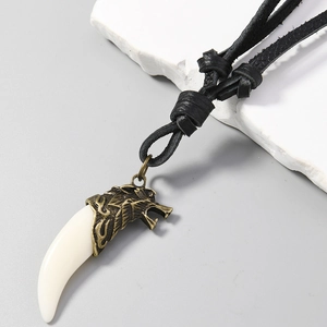 Détail macro du pendentif tête de loup en bronze et dent blanche avec cordon en cuir noir