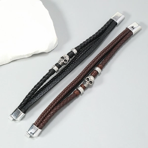 Detail of woven leather bracelets with skull charms and magnetic metal clasps