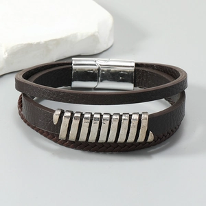 Macro shot of multi-layer braided leather bracelet with vintage silver charms and magnetic clasp