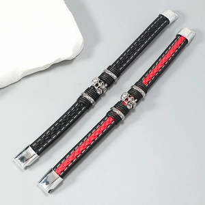 Detail view of woven leather bracelets featuring silver skull charms and magnetic metal clasps